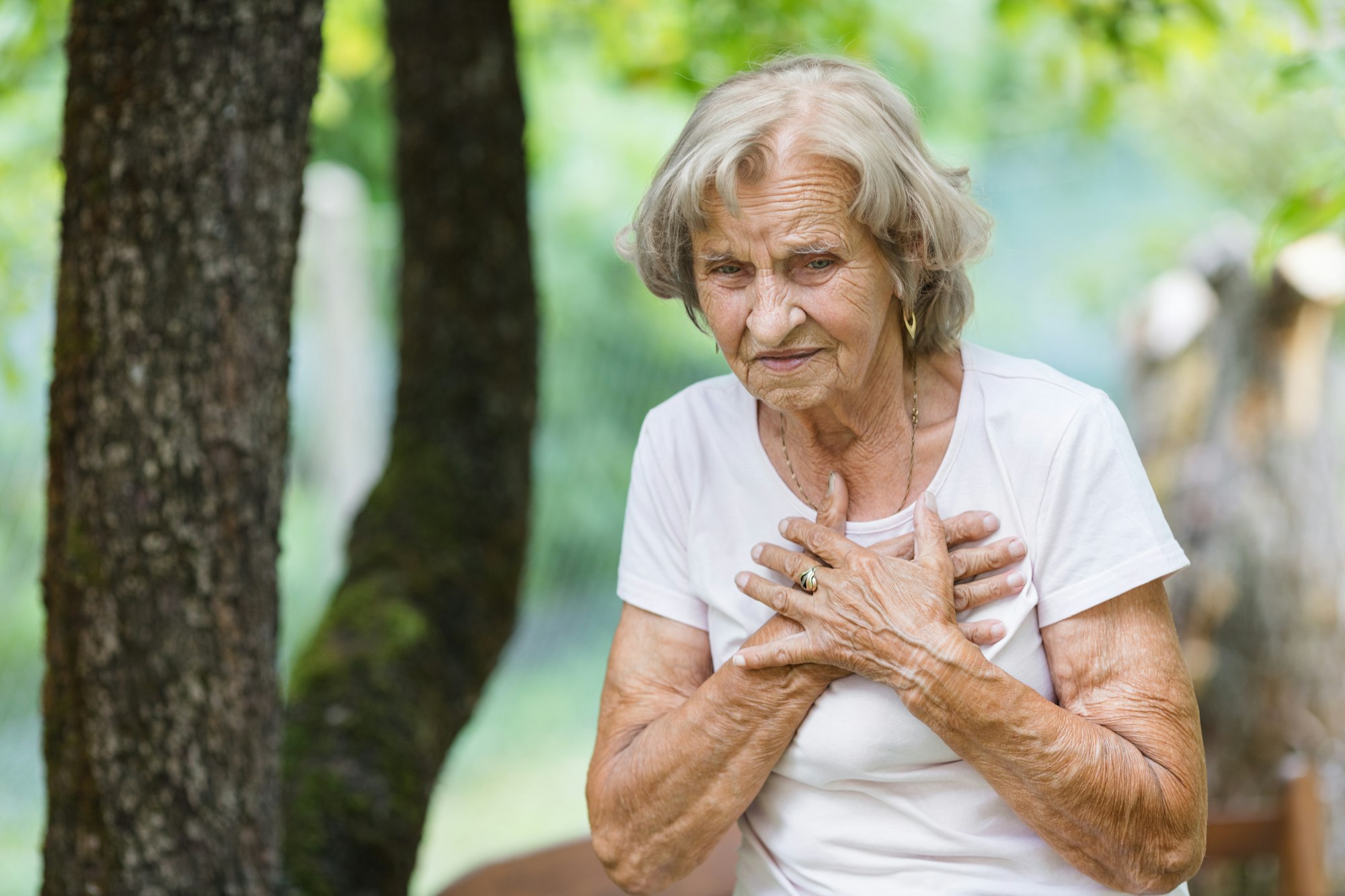 Elderly woman with heart pain holding her chest