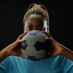 Female Football Player Holding Ball with Intense Face
