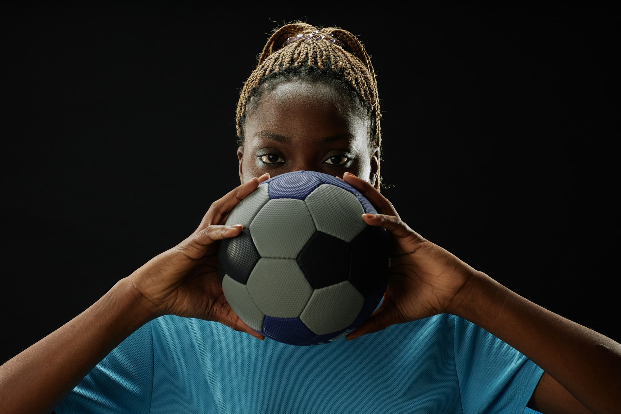 Female Football Player Holding Ball with Intense Face