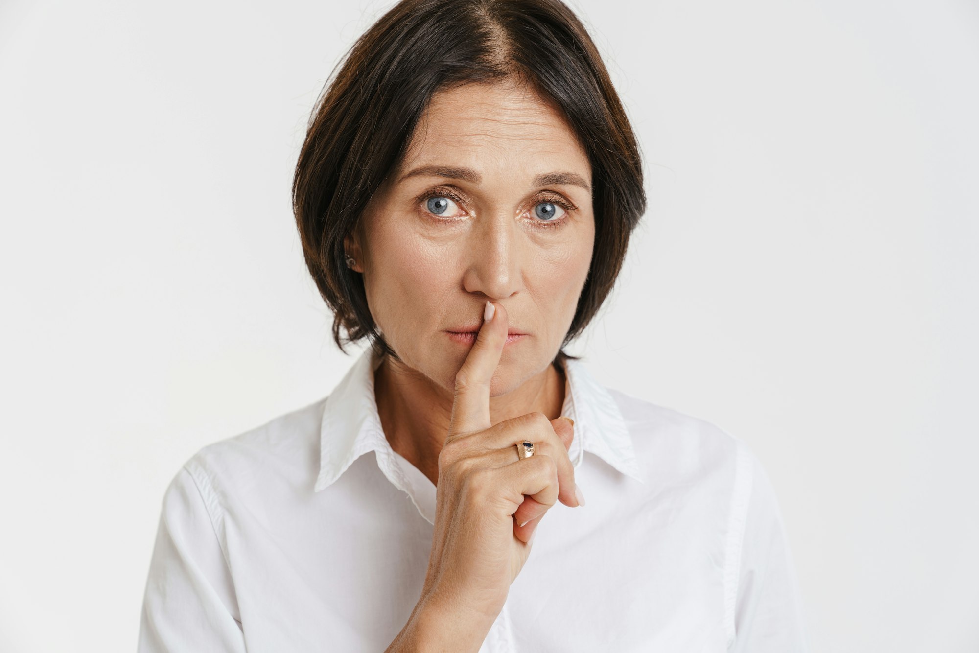 Mature brunette woman showing silence gesture at camera