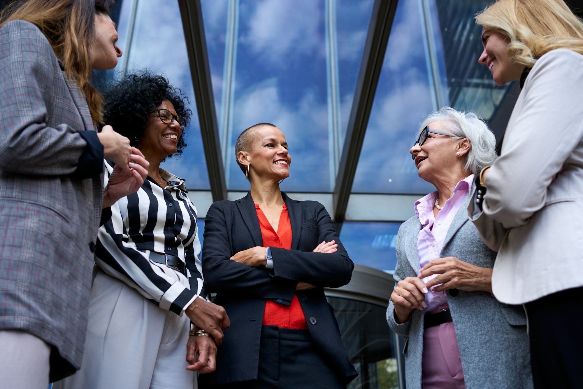 Team of cheerful business women of various ages and races happy outside the office building