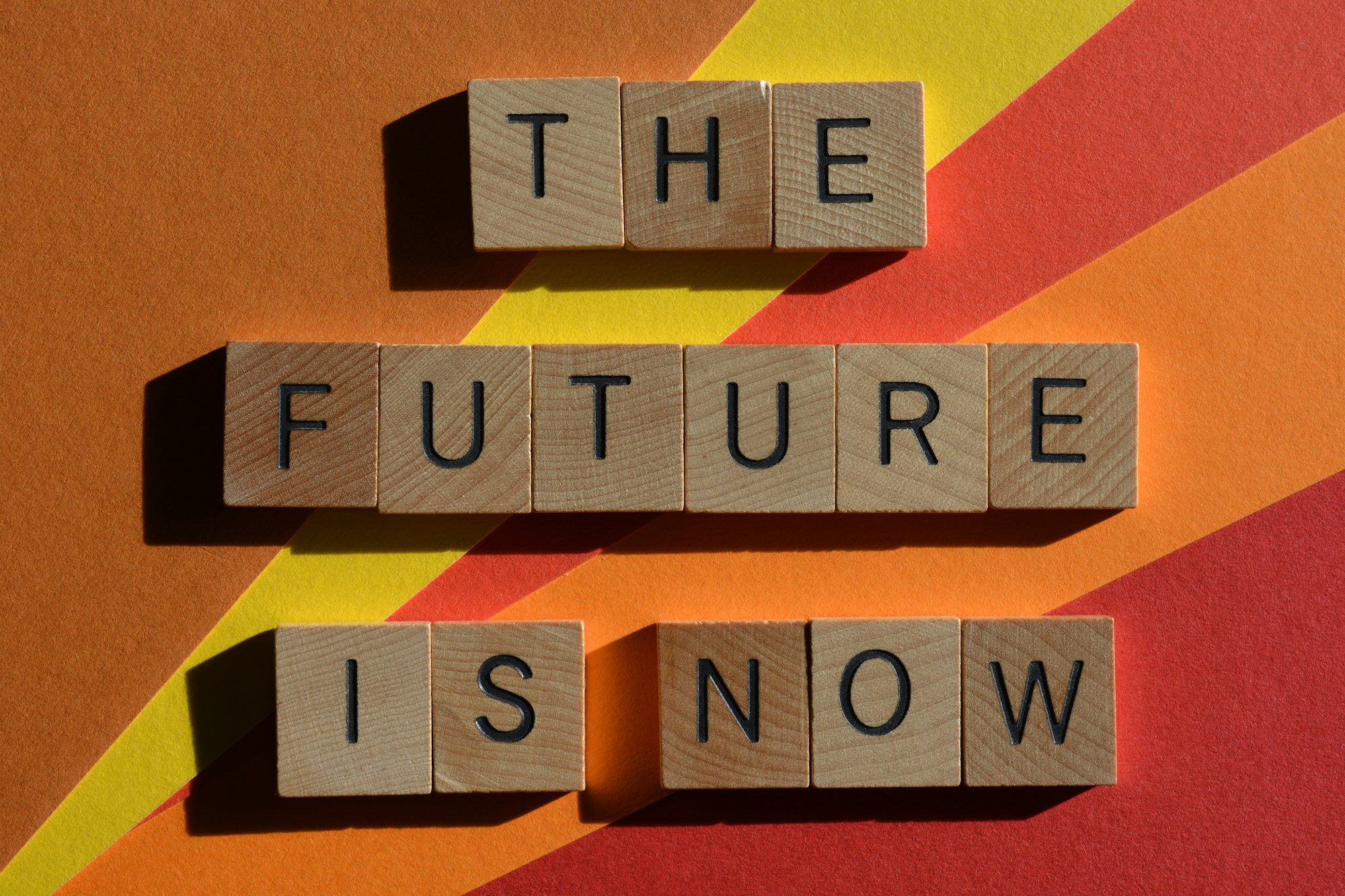 The Future Is Now, phrase in wooden alphabet letters on colourful background