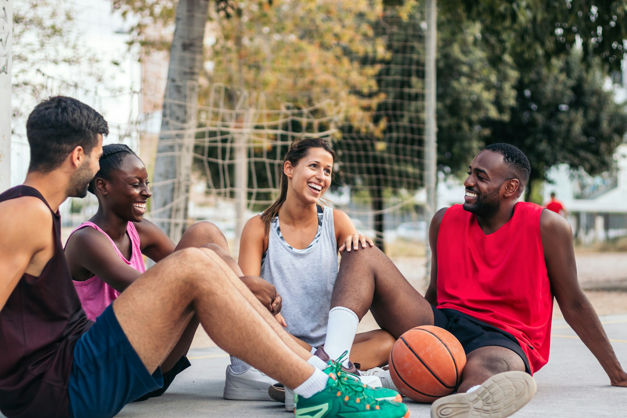 Friends sitting on the court talking after a basket game