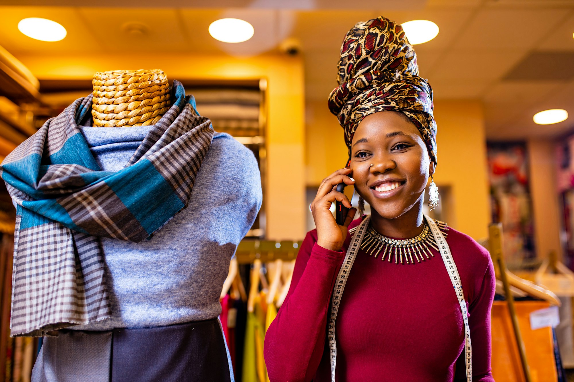 tanzanian woman with snake print turban over hear working in fabrics shop calling to client by