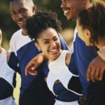 Team, hug or happy cheerleaders with support outdoor in training or sports event together on field.